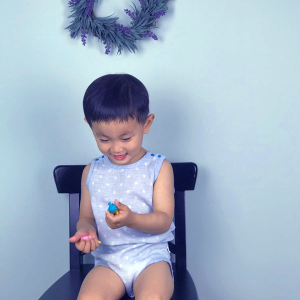toddler boy wearing blue GOTS certified organic cotton bodysuit sitting on chair