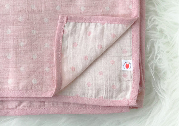 Folded pink GOTS certified organic cotton blanket in Versatile size for use as a stroller cover, or nursing cover