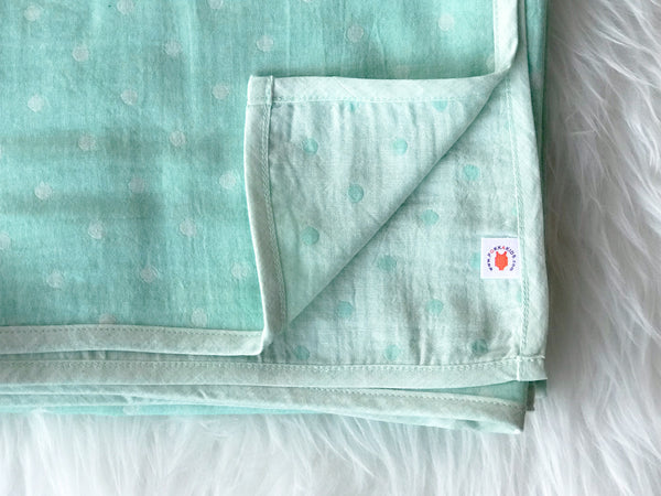 Folded mint polka dot GOTS certified organic cotton blanket for use as a stroller cover, or nursing cover